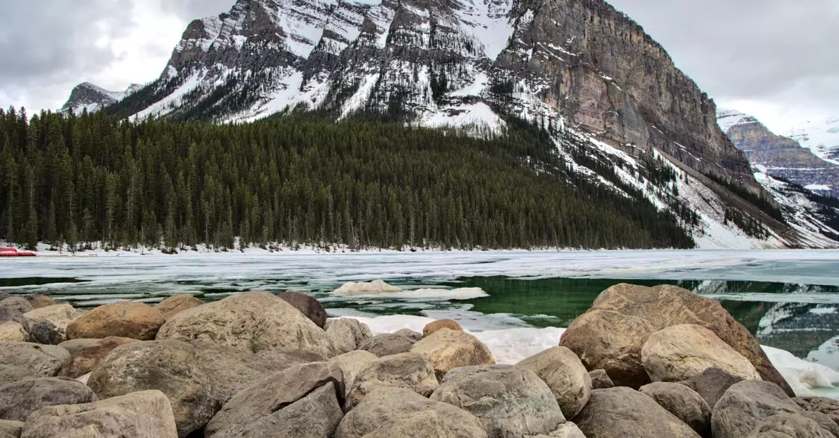 A stunning view of the snow-covered mountains and partially frozen Lake Louise in Canada.