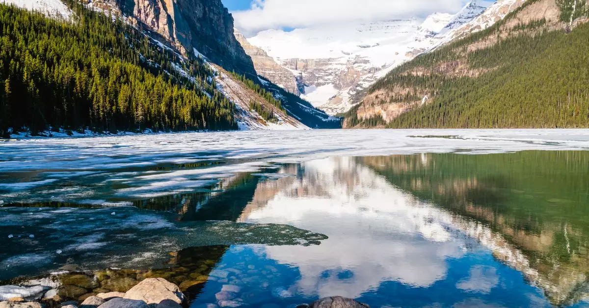 A breathtaking view of Lake Louise with snowy mountains reflecting in the water.
