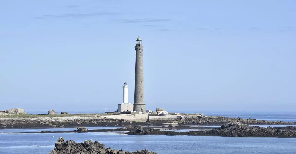 A majestic lighthouse on rocky seashore with clear blue sky, capturing the serene coastal landscape.