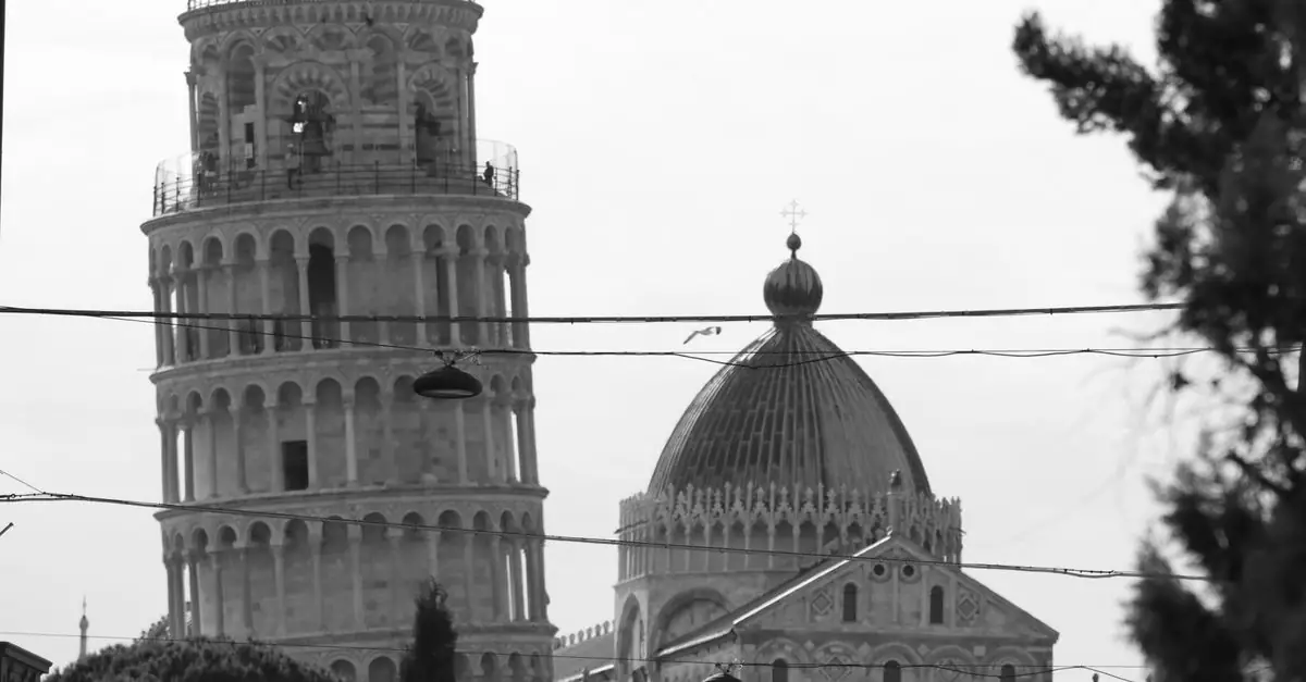 Black and white image of Pisa's Leaning Tower and Cathedral captured from street view.