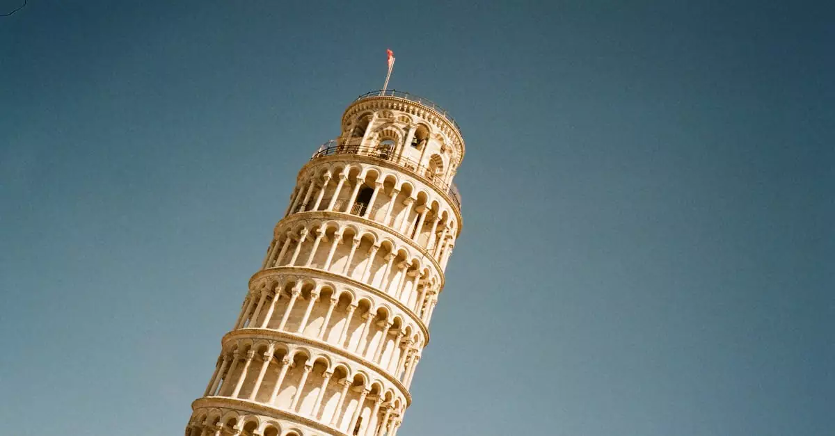 Iconic low angle view of the Leaning Tower of Pisa with a clear blue sky overhead, emphasizing its architectural beauty.
