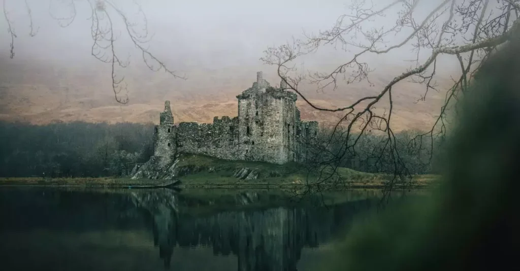 A fog-laden medieval castle with a reflection in a misty lake creates an eerie and historic scene.