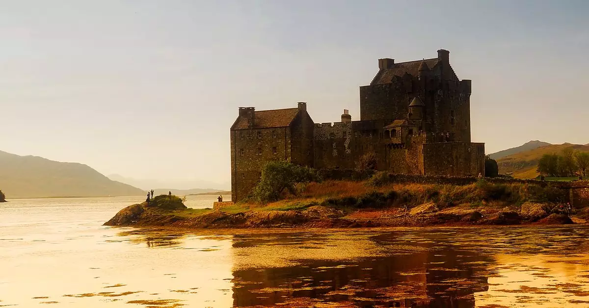 A stunning view of Eilean Donan Castle reflected in the loch during sunset in the Scottish Highlands.