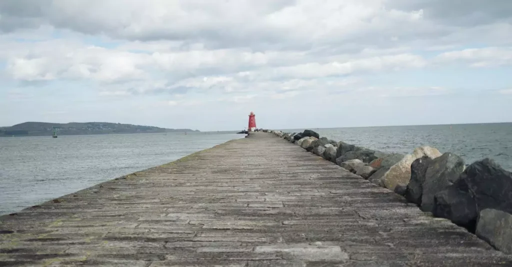 Dublin's Lesser-Known Beaches: Your Coastal Guide 2 Scenic view of Poolbeg Lighthouse along the stone pier extending into the sea under cloudy skies.