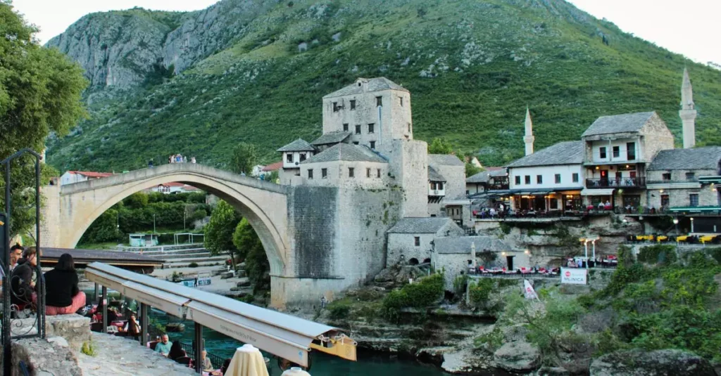 Explore the historic Old Bridge in Mostar, surrounded by lush hills and vibrant architecture.