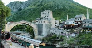 Explore the historic Old Bridge in Mostar, surrounded by lush hills and vibrant architecture.