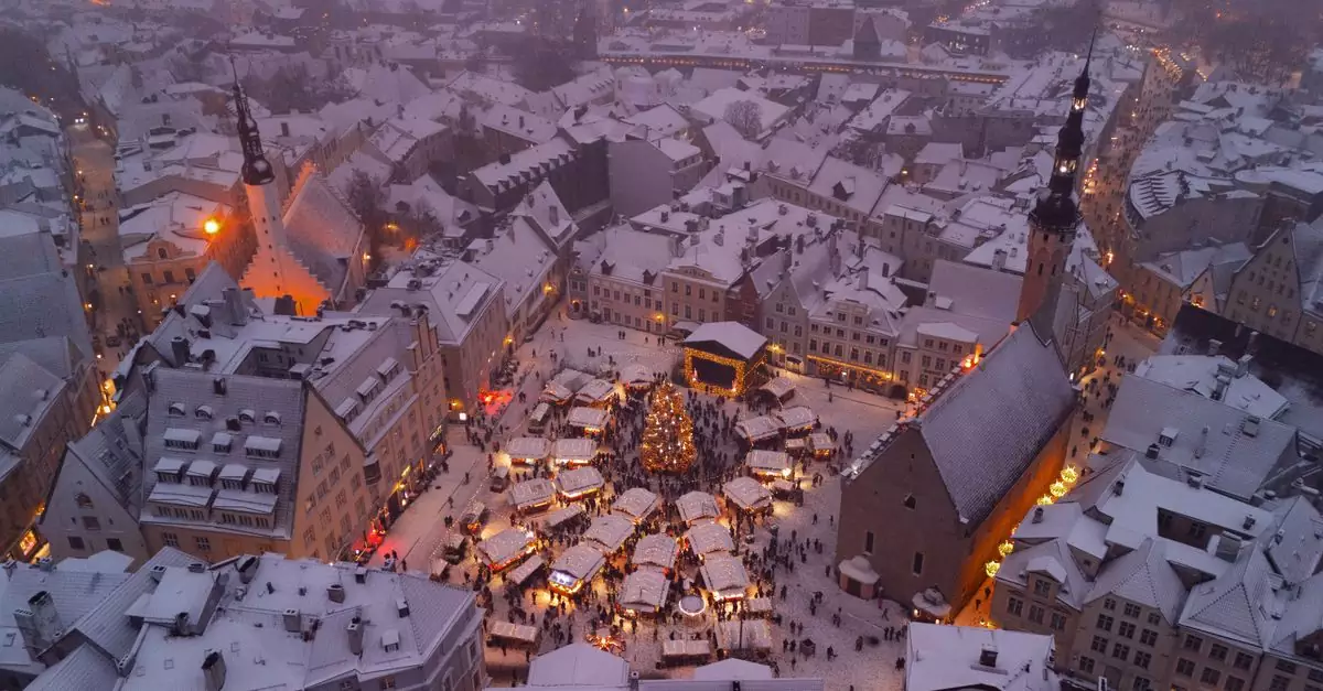 A scenic aerial shot of snowy Tallinn's Christmas market with twinkling lights at dusk.