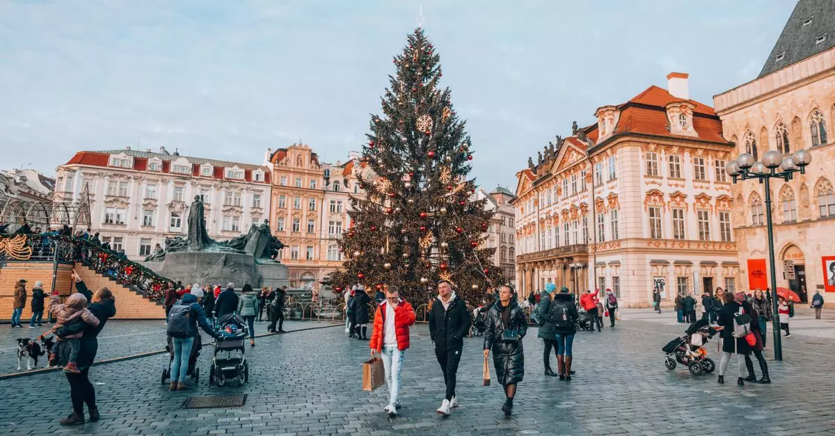 People walking through a festive Christmas market in a historic European town square during winter.