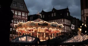 Illuminated vintage carousel in a historic town square during twilight.