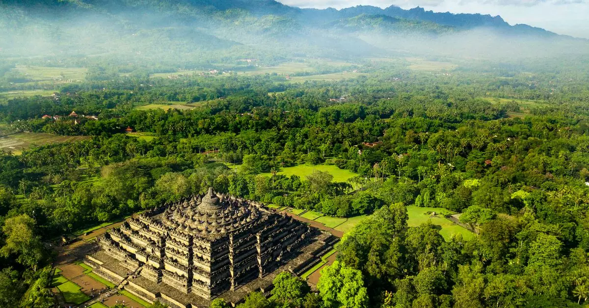 Stunning aerial view of Borobudur Temple surrounded by lush greenery in Central Java, Indonesia.