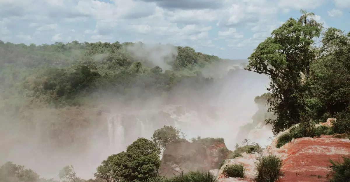 Scenic view of Iguazu Falls with mist and lush greenery. Perfect for nature and travel enthusiasts.