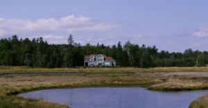 Charming rural landscape with a house by a meandering river in St. Andrews, Canada.