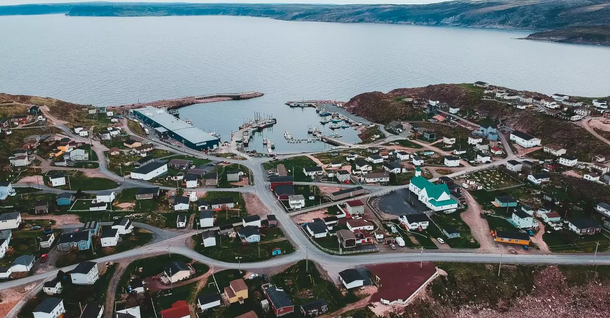 Aerial view of various houses located near calm rippled sea water under gray sky in gloomy weather