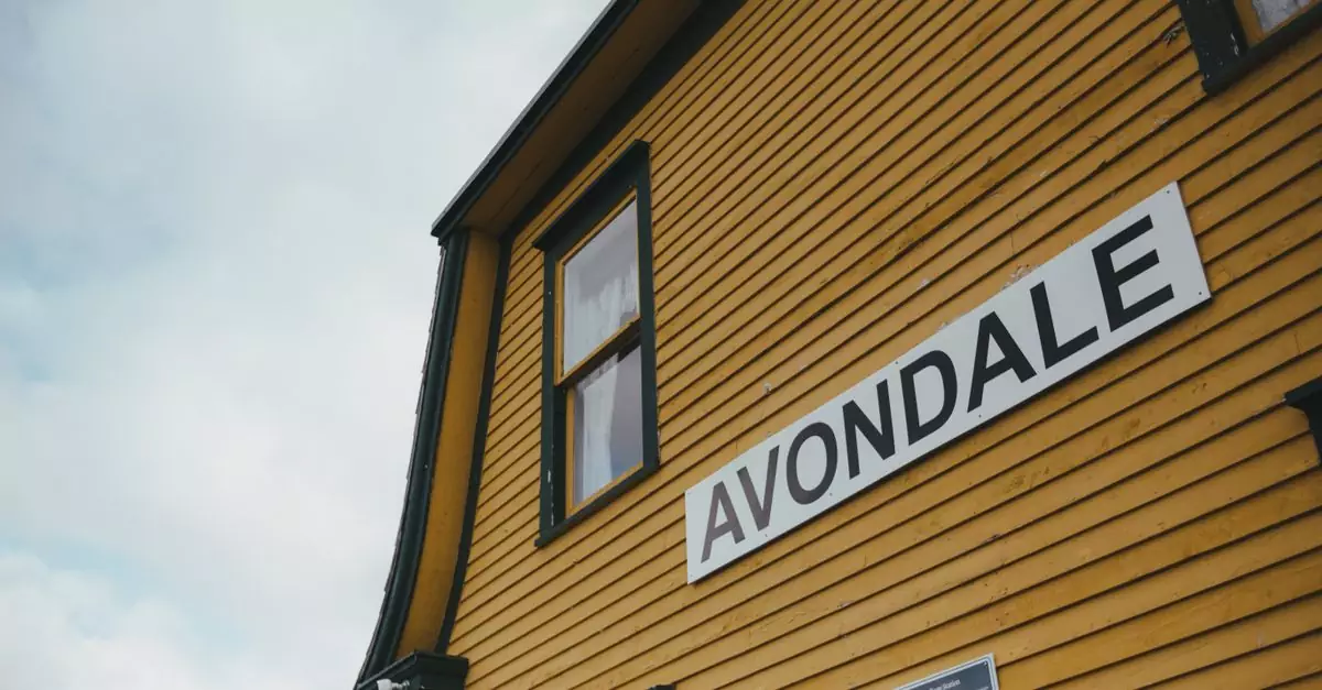 Low angle view of a yellow wooden building with Avondale signage and a cloudy sky.