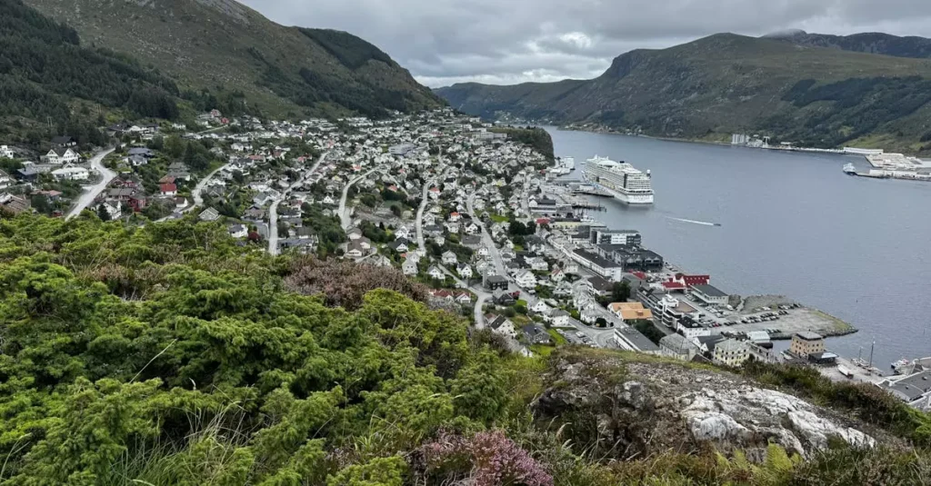 Aerial view of a Norwegian town beside a fjord, surrounded by mountains.