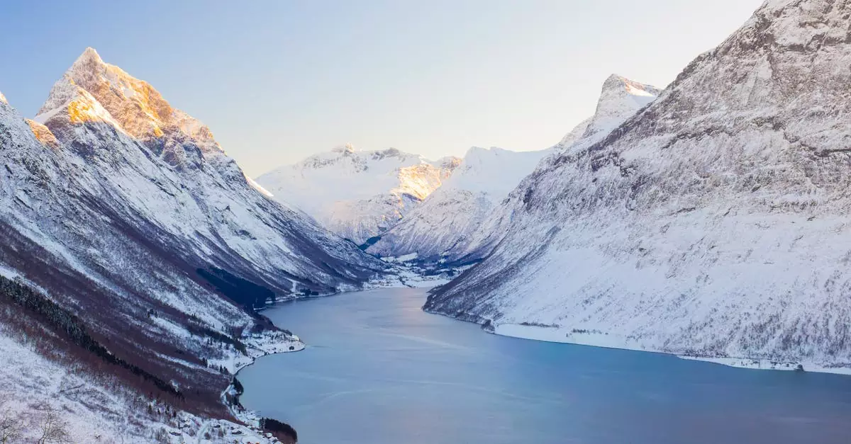 A breathtaking view of snow-covered Norwegian fjords under bright winter sunlight.