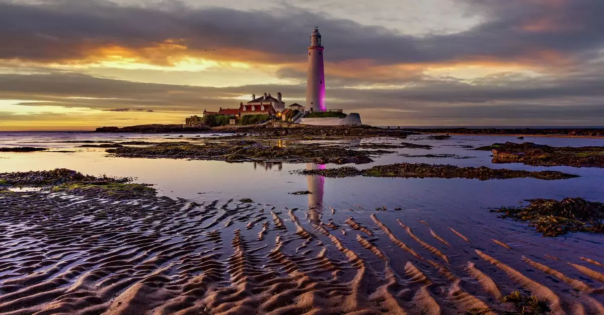Scenic view of St Mary's Lighthouse with vibrant sunset reflections.