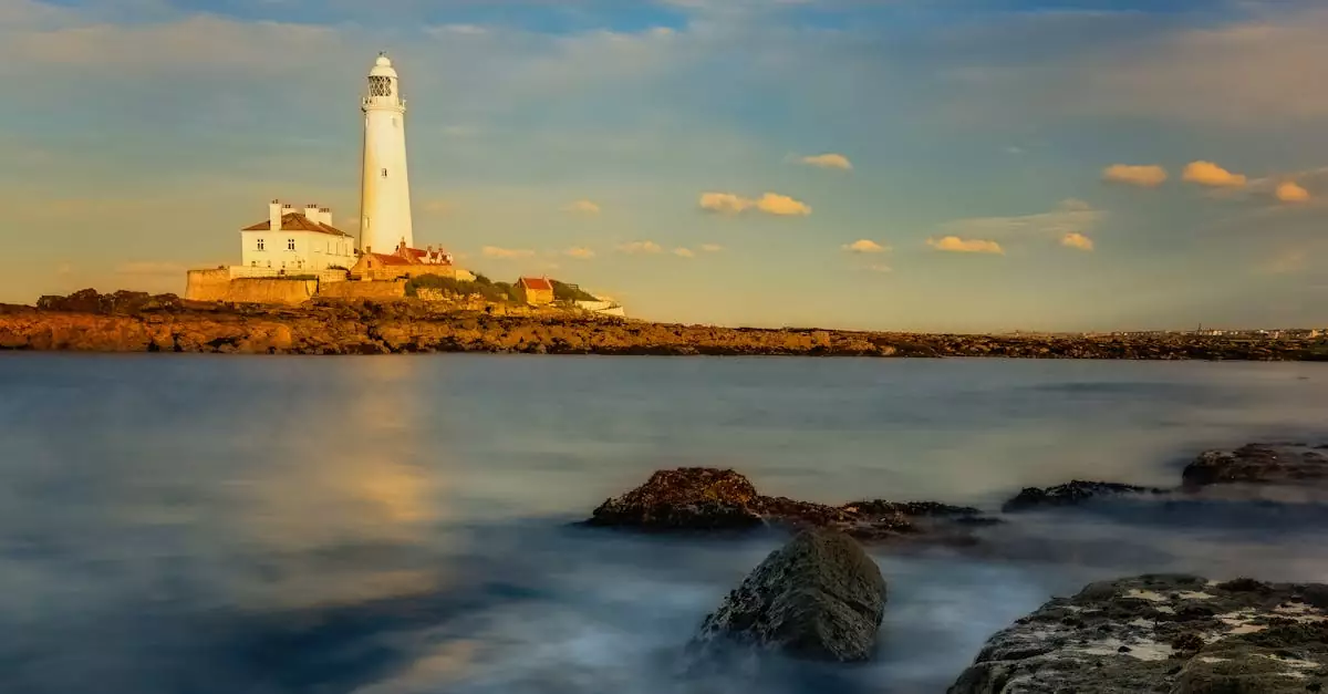 Stunning sunset view of St Mary's Lighthouse with calm sea and rocks in foreground.