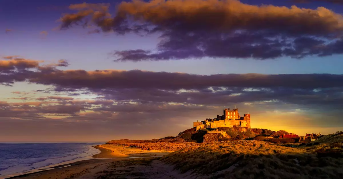 A captivating sunset casting vibrant hues over a historic coastal castle with dramatic skies.