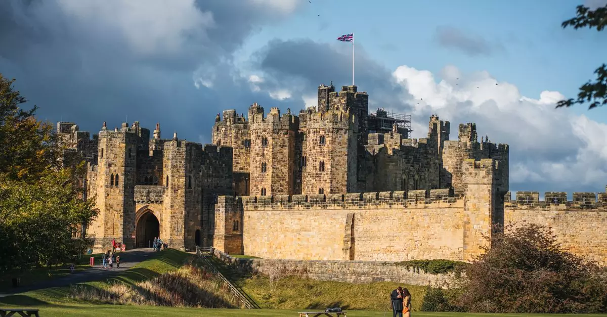 Explore the historic Alnwick Castle in England, captured under a stunning sky with autumn hues.