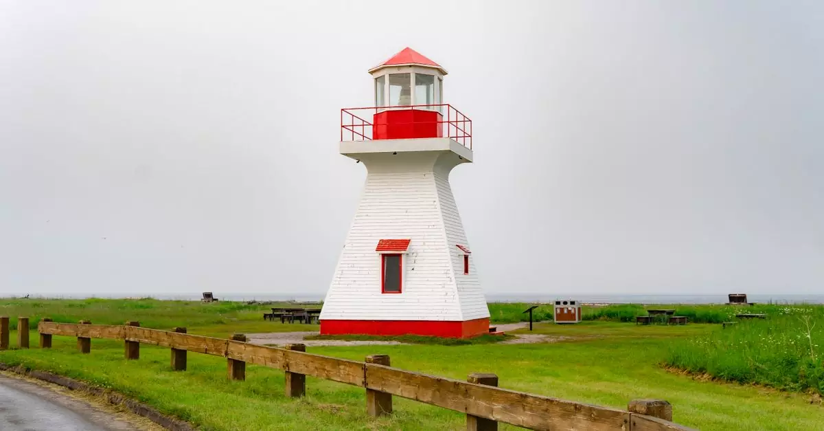 Charming red and white lighthouse on a coastal landscape in rural Canada, ideal for tourism and travel imagery.