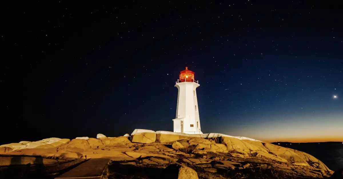 Captivating night view of Peggy&rsquo;s Point Lighthouse under a starry sky in Canada.