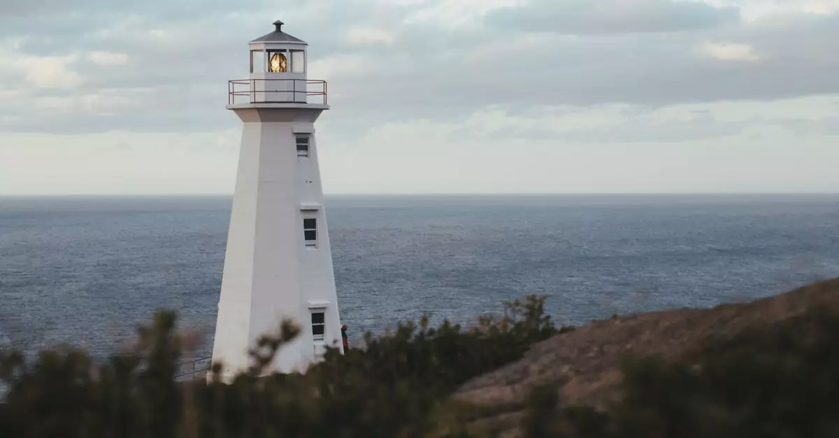A serene lighthouse standing tall by the ocean under a cloudy sky.