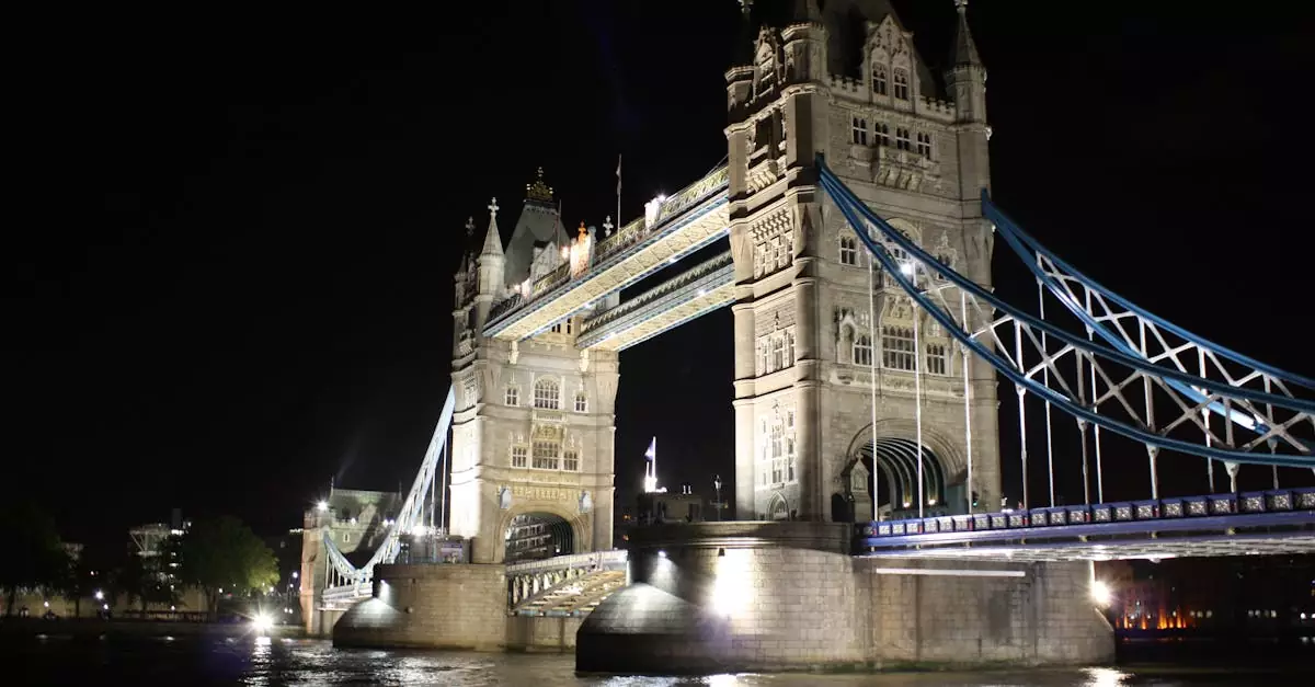 Illuminated Tower Bridge reflected on the Thames at night in London, showcasing architectural beauty.