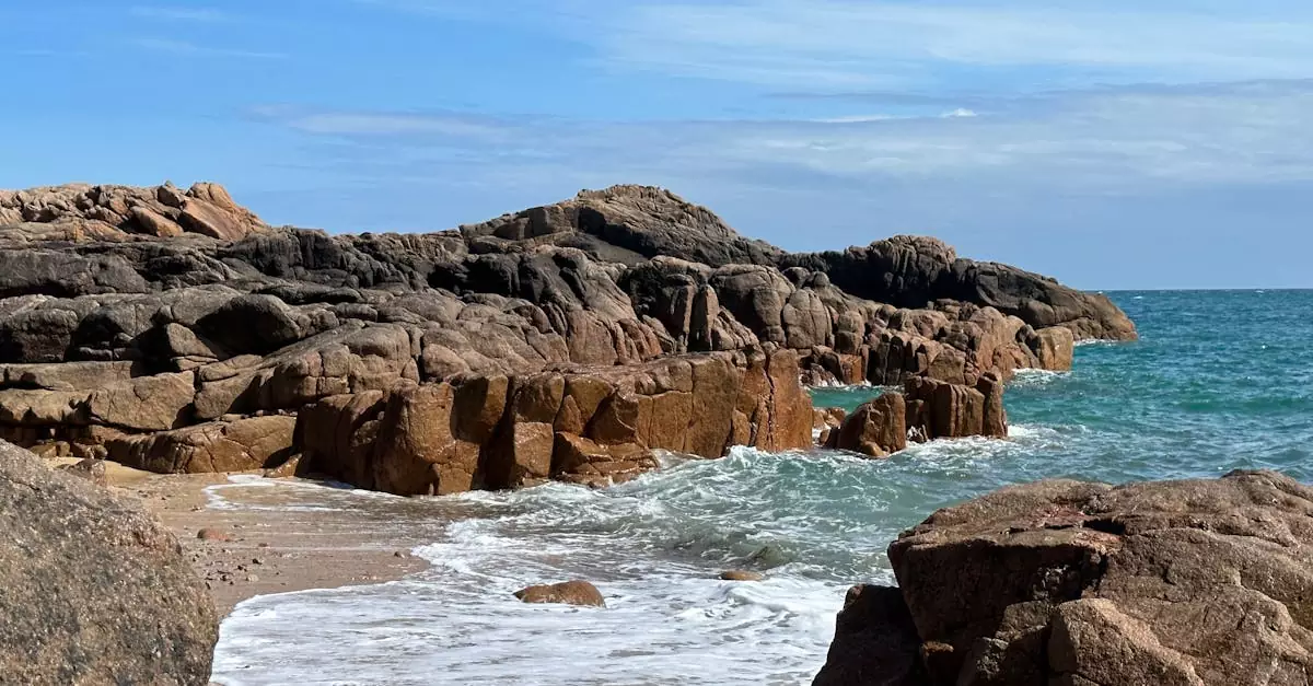 Scenic view of rocky coastline with waves crashing at Corbiere Point, Jersey. Perfect summer day for travel enthusiasts.