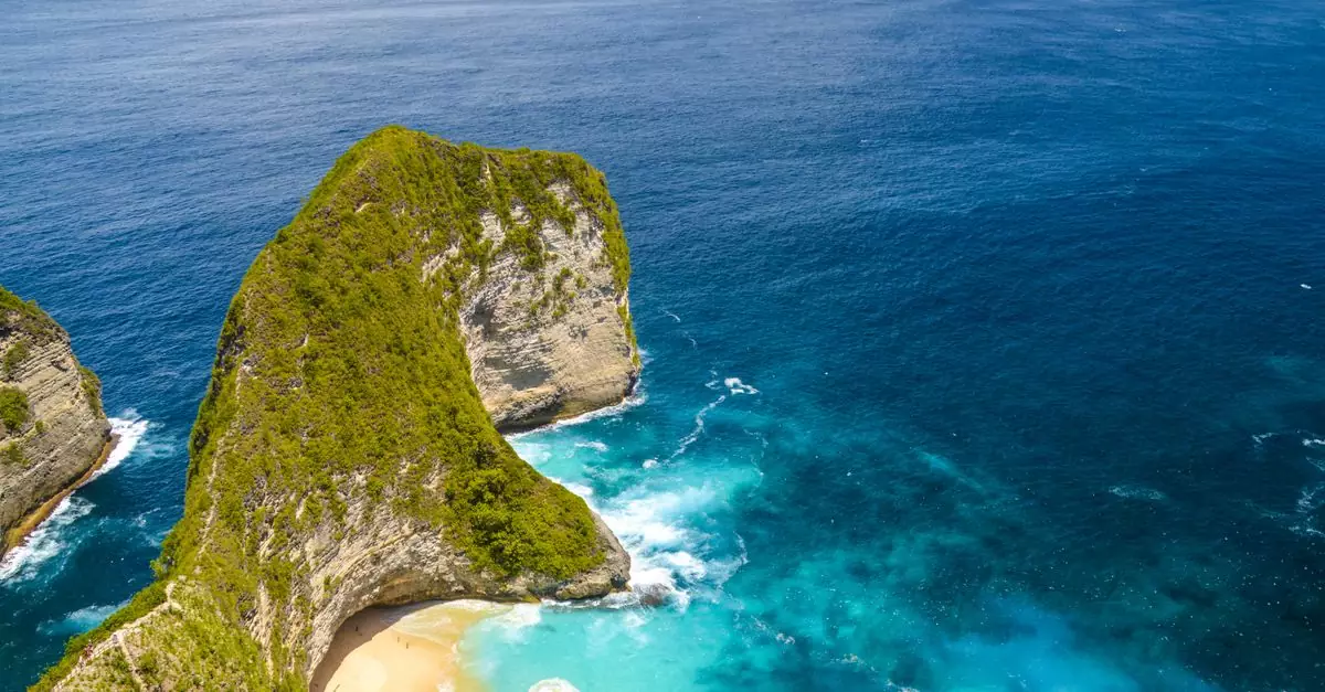 Stunning aerial view of Kelingking Beach's turquoise waters and unique rock formations in Bali, Indonesia.