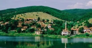 Scenic view of a tranquil village by the lake in Günyurdu, Türkiye, showcasing lush greenery and a serene atmosphere.