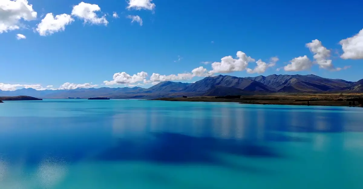 Stunning view of a turquoise mountain lake with scenic clouds and serene landscape.