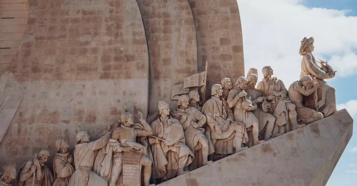 Close-up of the Monument of the Discoveries in Lisbon, showcasing historic figures in sculpted detail under a clear sky.