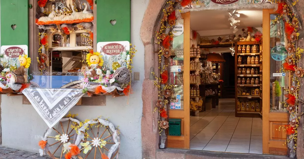Colorful facade of a shop in Riquewihr, France, with floral decor and rustic elements.