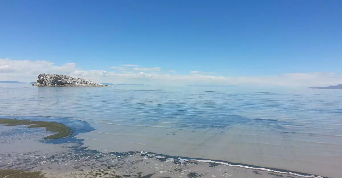 A tranquil seascape of Antelope Island viewed from Syracuse beach, Utah, under a clear blue sky.
