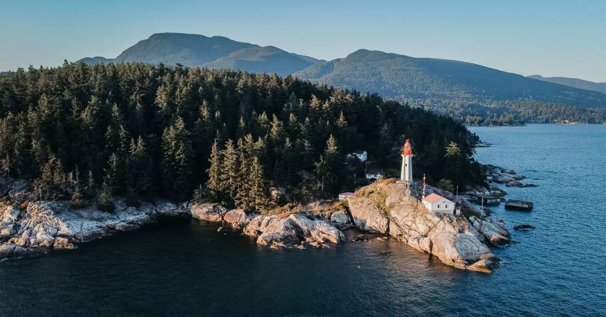 Aerial view of a lighthouse on rocky shoreline surrounded by forest in West Vancouver, BC, Canada.