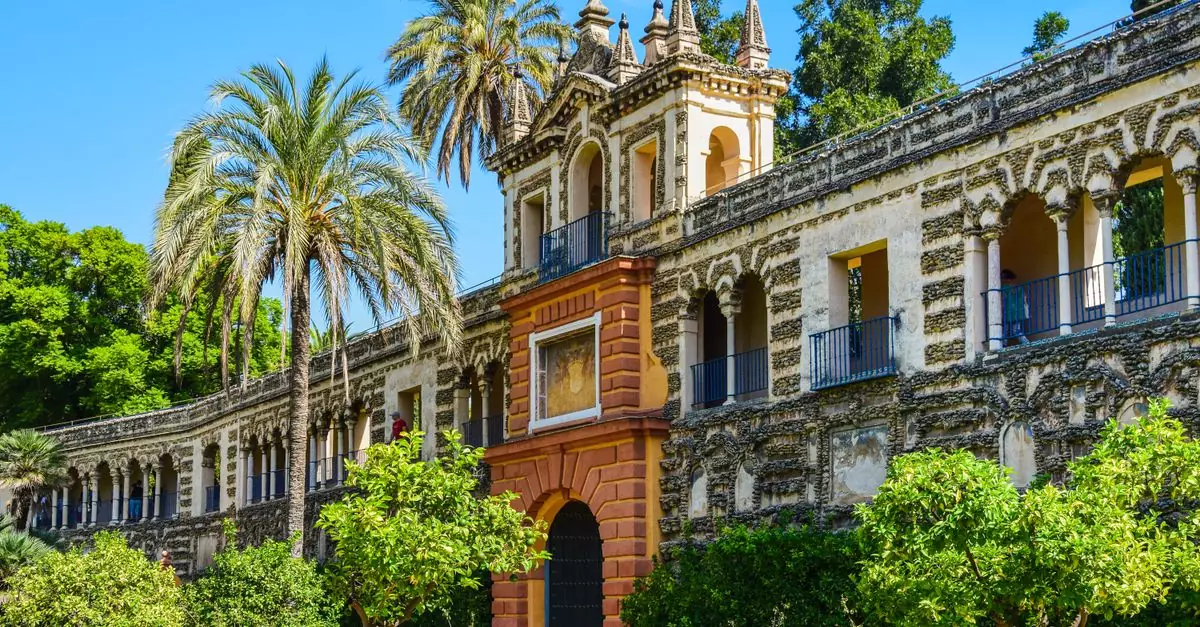 Discover the stunning Alcazar Palace with lush gardens, palm trees, and historic architecture in Seville, Spain.