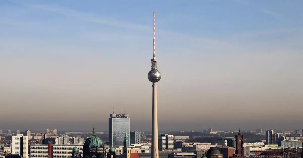 Admire Berlin's urban skyline featuring the iconic Fernsehturm tower against a clear blue sky.