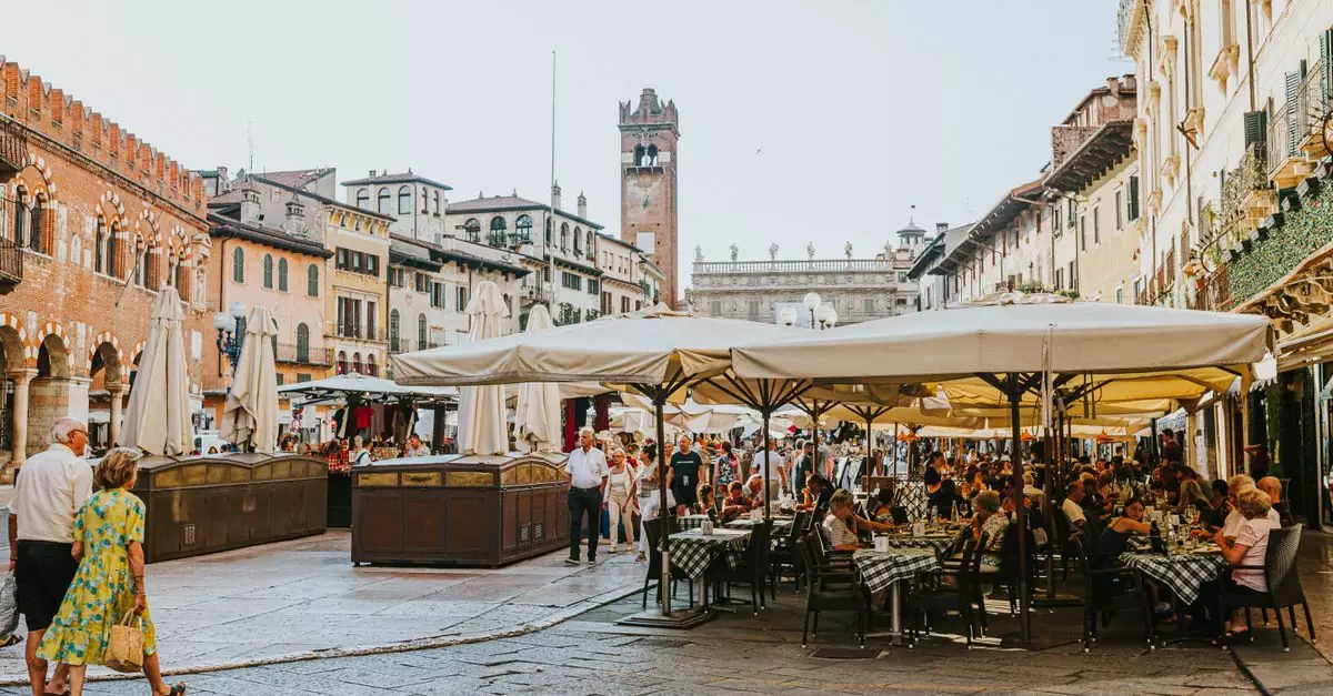 Bustling dining scene at Piazza delle Erbe, Verona, with tourists enjoying al fresco dining.