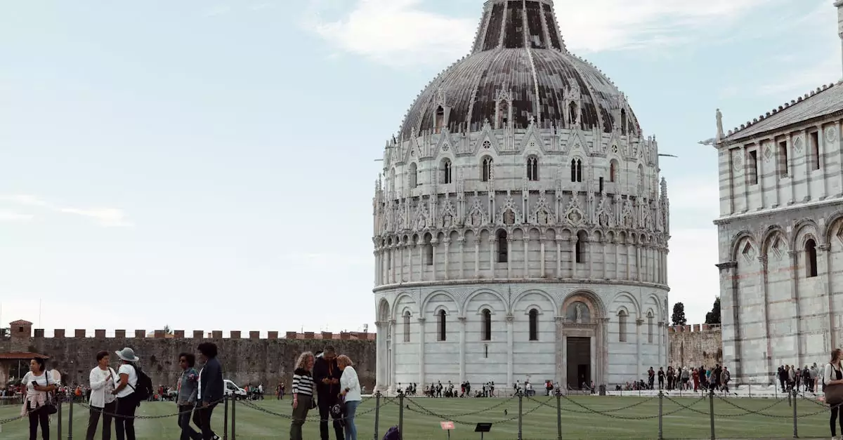 View of the San Giovanni Baptistery in Pisa with tourists, showcasing its architectural beauty.
