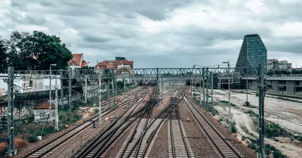 View of railway tracks and urban landscape in Poznań, Poland, under a cloudy sky.