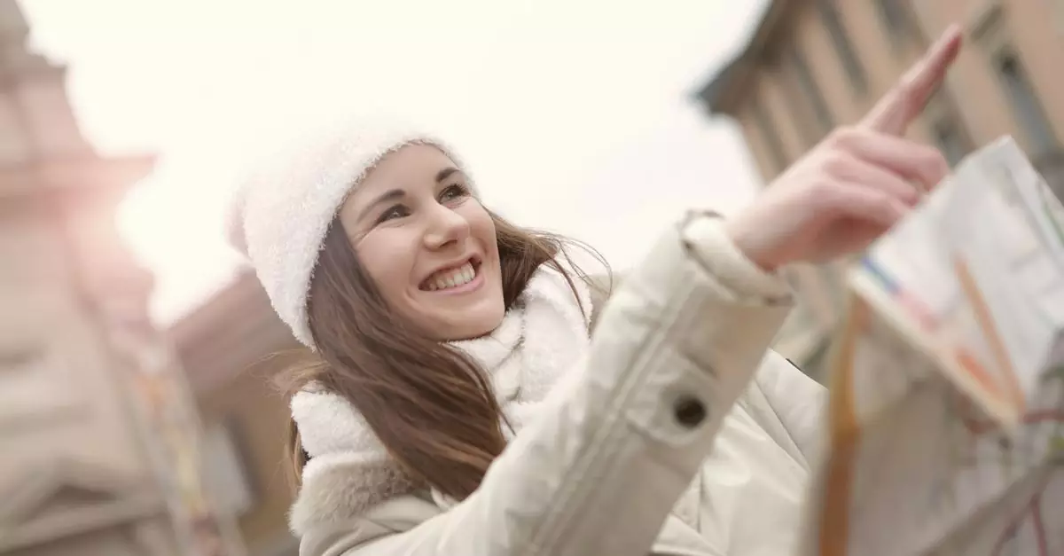 Cheerful young woman using map while looking for historical sightseeing and pointing direction