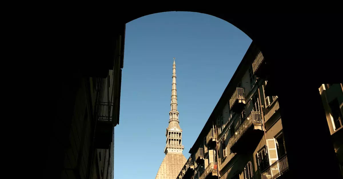 View of Mole Antonelliana under a blue sky, framed by an archway in Turin, Italy.